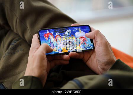 Pokemon GO gioco iOS mobile su schermo dello smartphone iPhone 15 in mani maschili durante l'azione di gioco mobile. Giochi e intrattenimento mobili su dispositivi portatili Foto Stock
