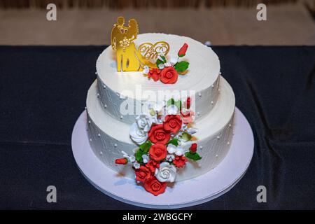 torta nuziale bianca con bambole che rappresentano la sposa e lo sposo in cima. Foto Stock