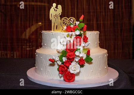 torta nuziale bianca con bambole che rappresentano la sposa e lo sposo in cima. Foto Stock