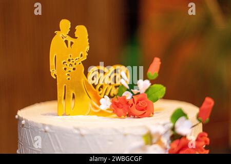 torta nuziale bianca con bambole che rappresentano la sposa e lo sposo in cima. Foto Stock