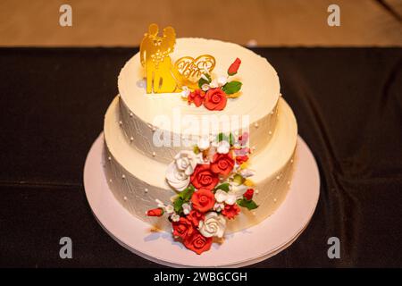 torta nuziale bianca con bambole che rappresentano la sposa e lo sposo in cima. Foto Stock