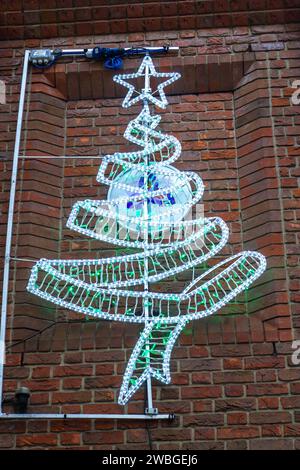 Un albero di Natale natalizio fatto di luci è esposto su una parete di mattoni a Saffron Walden, Essex, Regno Unito. Le luci sono bianche e verdi. Foto Stock