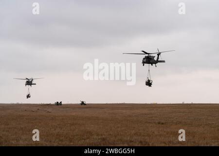 Soldati d'artiglieria con Alpha 'Gator' Battery, 3rd Battalion, 320th Field Artillery Regiment, 3rd Brigade Combat Team, 101st Airborne Division, 'Task Force 82,' addestramento di slitta a carico della Mihail Kogalniceanu Air base, Romania, 9 gennaio 2024. Gli elicotteri UH-60 Black Hawk del 3rd Attack Helicopter Battalion, 1st Aviation Regiment, 1st Combat Aviation Brigade, 1st Infantry Division, supportarono i 101st Airborne Division Artillery Soldiers spostando gli obici M119 per via aerea per aumentare la competenza nei loro compiti di combattimento di guerra. (Foto dell'esercito degli Stati Uniti del Sgt. 1st Class Jonathan Hornby) Foto Stock