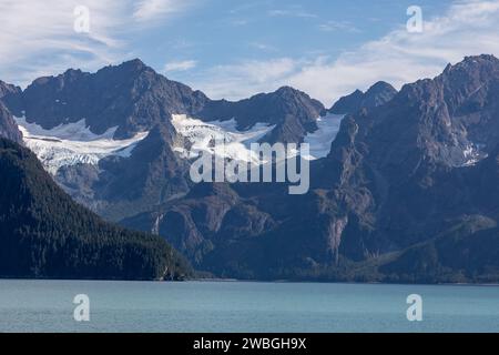 Ghiacciai e picchi frastagliati si innalzano sopra le calme acque blu dell'oceano in una natura incontaminata dell'Alaska Foto Stock