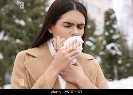 Donna in cappotto tossisce all'aperto. Sintomi del raffreddore Foto Stock