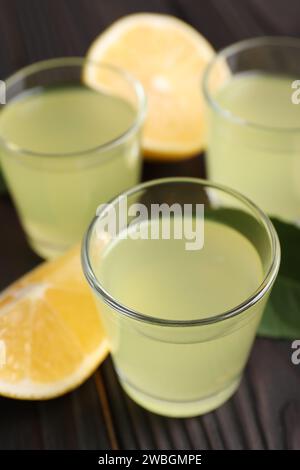 Gustoso liquore al limoncello e limone su tavola di legno scuro, primo piano Foto Stock