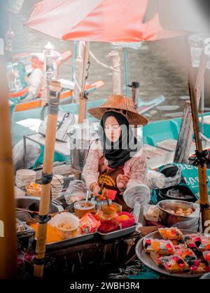 Hat Yai, Thailandia - 15 dicembre 2023: Una donna Hijab che prepara il pasto al mercato galleggiante di Khlong Hae. Visita la Thailandia. Foto Stock