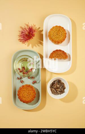 Una manciata di semi di girasole esposti con alcune torte lunari e una tazza di tè con fiori secchi. Le usanze di celebrare il Mid-Autumn Festival in Foto Stock