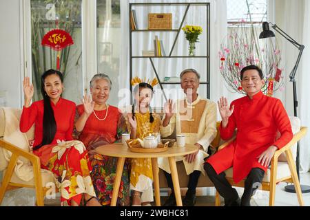 Ritratto di una grande famiglia vietnamita che beve un tè con prelibatezze quando festeggia il Tet a casa Foto Stock