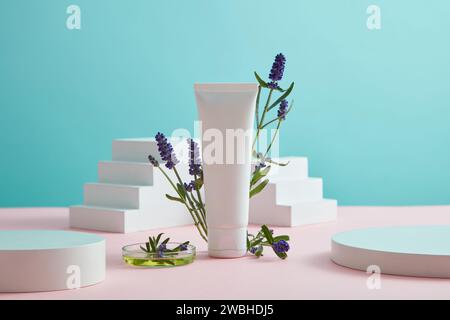 Scena di mockup per pubblicità e branding di cosmetici con ingredienti di lavanda. Provetta di plastica bianca su sfondo blu con lavanda in fiore Foto Stock