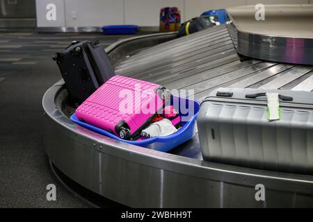 Valigetta rotta collocata in un cestello di plastica. Valigie sul nastro trasportatore per bagagli nel ritiro bagagli all'aeroporto. Foto Stock