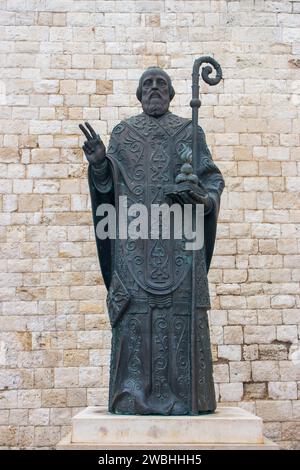 Statua di San Nicola contro il muro di pietra in Italia, Bari. Monumento d'arte italiana. Concetto di cultura religiosa. Concetto di religione e fede. Foto Stock