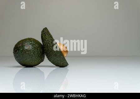 Foto accattivante con un avocado fresco collocato su un tavolo bianco in un ambiente minimalista, evidenziando il suo gusto vivace e sano Foto Stock