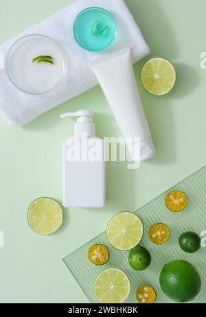 Piatti Petri di liquido blu e buccia messi su un asciugamano bianco. Contenitori cosmetici decorati con fette di kumquat e lime. Gli agrumi sono noti per loro Foto Stock