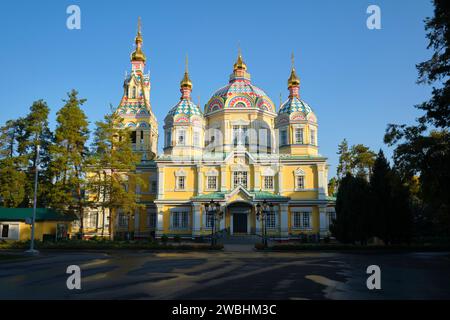 Vista della facciata laterale gialla con la piazza ombreggiata al mattino, soleggiata e luminosa. Presso l'Ascensione, la cattedrale di legno Zenkov nel parco Panfilov. Ad Almat Foto Stock