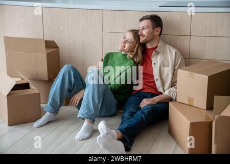 Coppia felice uomo donna che sogna la vita in un nuovo appartamento seduto sul pavimento Foto Stock