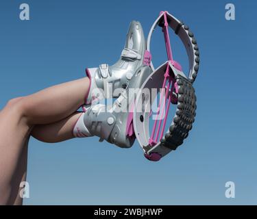 Vista ravvicinata delle gambe incrociate femminili in un raggio d'aria nello sport Kangoo salta gli stivali durante l'allenamento fitness all'aperto sullo sfondo del cielo blu Foto Stock