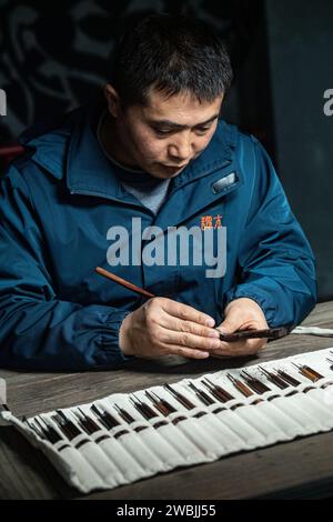 (240111) -- CHONGQING, 11 gennaio 2024 (Xinhua) -- Yu Dahong incide su un pettine di legno in un laboratorio della fabbrica Tanmujiang a Chongqing, nel sud-ovest della Cina, 5 gennaio 2024. L'artigianato tradizionale con pettine di legno di Tanmujiang, che combina l'abilità della decorazione a colori, dell'incisione, della laccatura e della doratura d'oro, sono stati elencati come patrimonio culturale immateriale del comune di Chongqing. Utilizzando bosso, ebano o legno di sandalo come materiali per intagliare motivi come personaggi, fiori e uccelli sui pettini, l'artigianato ha trasformato l'articolo comune nella vita quotidiana in un'opera d'arte con valori estetici. Foto Stock