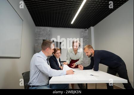 L'estrusione femminile valuta il lavoro dei subordinati. Progettisti ingegneri a una riunione. Foto Stock