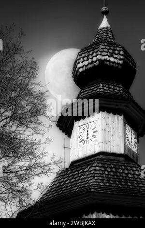 Campanile con orologio a una mano contro il cielo con Full Moon. Chiesa di San Lorenzo, Perniö, Salo, Finlandia. Conversione monocromatica. Foto Stock