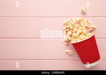 Deliziosi popcorn su sfondo di legno rosa chiaro. Vista dall'alto Foto Stock