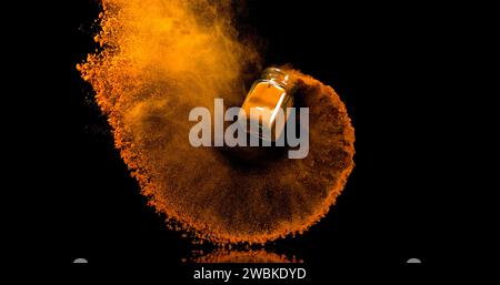 Curcuma, curcuma longa, polvere in un piccolo barattolo che cade su sfondo nero, Indian Spice Foto Stock