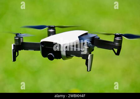 Primo piano di un drone aereo che si libra nell'aria con uno sfondo verde Foto Stock