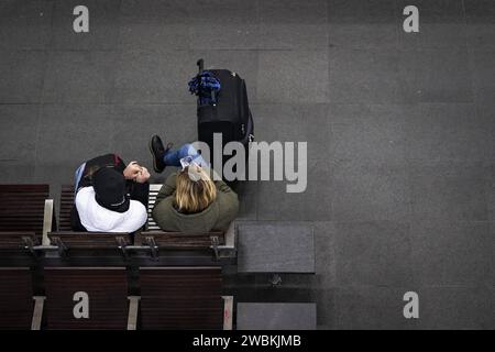 AM Berliner Hauptbahnhof sitzen zwei wartende Personen mit Koffer. Heute ist der zweite Tag des Streiks der Lokfuehrergewerkschaft GDL, an dem mit Zugausfaellen zu rechnen ist. Berlino, 11.01.2024. Berlin Deutschland *** due persone in attesa con le valigie si siedono alla stazione centrale di Berlino oggi è il secondo giorno dello sciopero dei macchinisti union GDL, su cui ci si aspetta la cancellazione del treno Berlino, 11 01 2024 Berlino Germania Copyright: XKiraxHofmannx Foto Stock