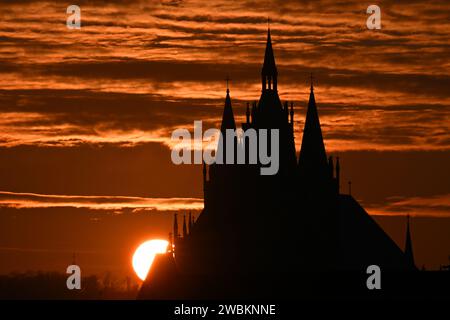 Vieselbach, Germania. 11 gennaio 2024. Il sole tramonta dietro St Cattedrale di Maria a Erfurt. La Germania continuerà a sperimentare il clima ghiacciato nei prossimi giorni. Ci si aspetta che nevi un po' di notte, soprattutto in Sassonia e Turingia. Credito: Martin Schutt/dpa/Alamy Live News Foto Stock