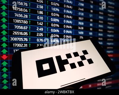 Konskie, Polonia - 5 gennaio 2024: Logo di scambio di criptovalute OKX visualizzato sullo smartphone sullo sfondo dei dati di mercato delle criptovalute Foto Stock