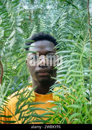 Ritratto di un giovane afroamericano dietro la vegetazione. Ritratto artistico Foto Stock