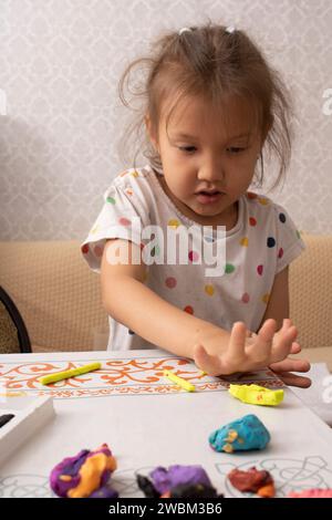 Una bambina che crea giocattoli dalla plasticina. Foto verticale Foto Stock