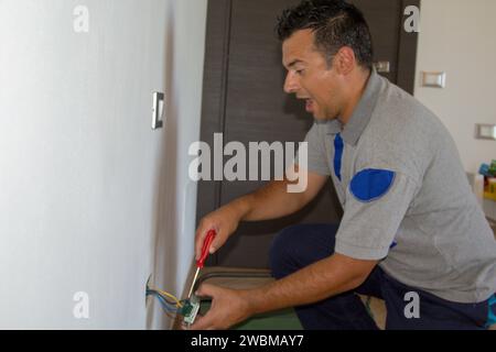 Immagine di un elettricista mentre installa una spina elettrica e riceve una scossa elettrica. Sicurezza del lavoro Foto Stock