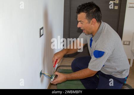 Immagine di un elettricista mentre installa una spina elettrica e riceve una scossa elettrica. Sicurezza del lavoro Foto Stock