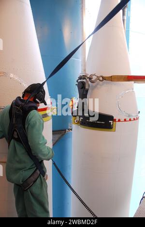 Un tecnico in un'imbracatura di sicurezza monitora l'attacco di un motore a razzo solido al razzo Delta II presso la Vandenberg Air Force base per il lancio del satellite NPP della NASA. Foto Stock