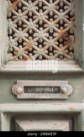 Primo piano di una porta invecchiata verniciata di verde con un'intricata griglia metallica e una fessura per lettere (Porto, Portogallo) Foto Stock
