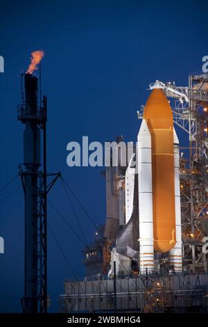 CAPE CANAVERAL, Ban. Lo Space Shuttle Atlantis viene rivelato sul Launch Pad 39A al Kennedy Space Center della NASA in Florida, bagnato da luci allo xeno a seguito dello spostamento della struttura di servizio rotante (RSS). La struttura fornisce protezione contro le intemperie e l'accesso alla navetta mentre attende il decollo sulla piattaforma. La torre a sinistra viene utilizzata per bruciare in sicurezza l'idrogeno in eccesso mentre lo shuttle è sul pad prima del lancio. La retrazione dell'RSS segna una pietra miliare nel conto alla rovescia della missione STS-135 di Atlantis. Atlantis e il suo equipaggio di quattro persone; il comandante Chris Ferguson, il pilota Doug Hurley, Mission specialis Foto Stock