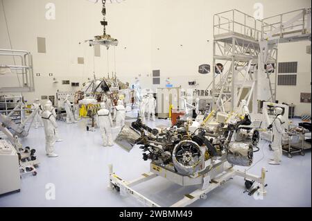 CAPE CANAVERAL, Ban. – Presso la Payload Hazardous Servicing Facility del Kennedy Space Center della NASA in Florida, i tecnici monitorano attentamente il fissaggio di una gru a ponte a uno stadio di discesa alimentato da razzi che sarà integrato con il rover Mars Science Laboratory (MSL) della NASA, noto come Curiosity (in primo piano). La fase di discesa abbasserà Curiosity alla superficie di Marte. Una configurazione United Launch Alliance Atlas V-541 verrà utilizzata per il loft di MSL nello spazio. I 10 strumenti scientifici di Curiosity sono progettati per cercare prove su se Marte abbia avuto ambienti favorevoli a mi Foto Stock