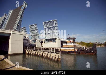 CAPE CANAVERAL, Ban. – Un rimorchiatore tira la Pegasus Barge attraverso un ponte levatoio dopo aver lasciato il Kennedy Space Center della NASA in Florida. La chiatta lunga 266 piedi e larga 50 piedi sarà trainata dalla nave Freedom Star della NASA per fornire attrezzature di supporto a terra per lo Space Shuttle Main Engine (SSME) allo Stennis Space Center vicino a Bay St. Louis, signorina. Da quando è stato consegnato alla NASA nel 1999, Pegasus ha navigato 41 volte e trasportato 31 serbatoi di carburante esterni navetta dalla Michoud Assembly Facility vicino New Orleans a Kennedy. La chiatta sta lasciando Kennedy, forse per l'ultima volta. Sia le attrezzature per chiatta che per la navetta Foto Stock