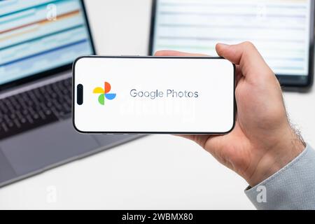 Logo Google Photos dell'app sullo schermo del telefono cellulare tenuto dall'uomo davanti al laptop e al tablet, dicembre 2023, Praga, Repubblica Ceca Foto Stock