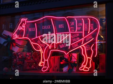 Diagramma dei tagli di carne di manzo alla macelleria. Cartello al neon nella finestra frontale del ristorante. Foto Stock