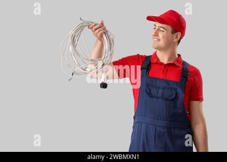 Elettricista maschio con cavi su sfondo chiaro Foto Stock