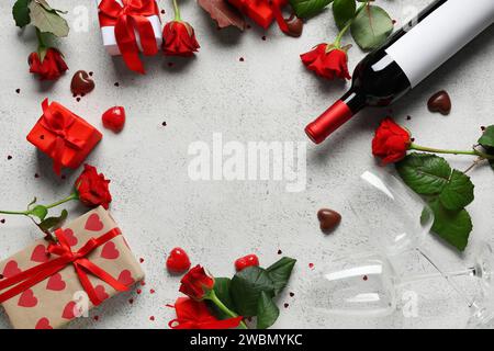 Cornice composta da rose rosse, bottiglia di vino, bicchieri, caramelle di cioccolato e confezioni regalo su sfondo bianco. Festa di San Valentino Foto Stock