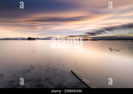 Lunga esposizione con acqua setosa per catturare un bellissimo tramonto nelle risaie allagate con un paesaggio idilliaco, Sueca, Valencia, Spagna. Foto Stock