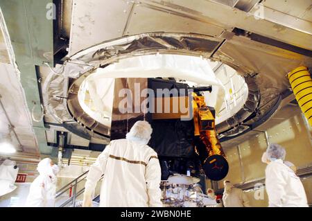 KENNEDY SPACE CENTER, FLA. - Nella torre di servizio mobile sul Launch Pad 17-B alla Cape Canaveral Air Force Station, Flag., i lavoratori guardano mentre la copertura protettiva che circonda la sonda Deep Impact viene rimossa. La carenatura verrà quindi installata intorno al veicolo spaziale. La carenatura è una struttura sagomata che si adatta perfettamente alla superficie esterna del booster dello stadio superiore Delta II e forma un giunto aerodinamico liscio, proteggendo la navicella durante il lancio e l'ascesa. Previsto per il decollo 12 gennaio, Deep Impact esplorerà sotto la superficie della Cometa Tempel 1 il 4 luglio 2005, quando la cometa Foto Stock