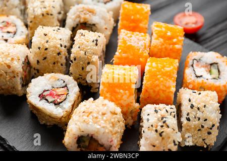 Set di sushi con salmone, tonno, caviale, semi di sesamo su un piatto di ardesia di pietra nera, primo piano. Foto Stock