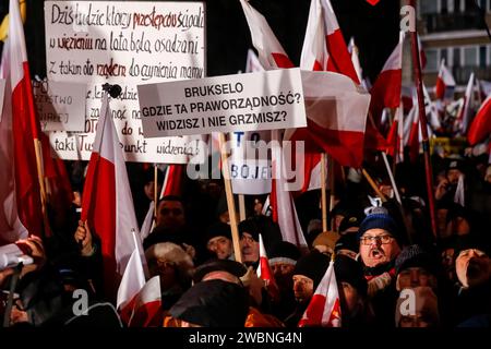 Varsavia, Polonia, 11 gennaio 2024. Folle di persone, con bandiere nazionali polacche e uno striscione che recita "Bruxelles - dove è il vostro Stato di diritto?”, guidato dal diritto e dalla giustizia (Prawo i Sprawiedliwość - PIS) i leader dei partiti politici protestano di fronte all'edificio del Parlamento polacco contro i cambiamenti nei media pubblici in Polonia e nella protezione della democrazia - dicono i politici del PIS. Il partito legge e giustizia governò in Polonia per 8 anni fino a quando non perse le ultime elezioni nell'ottobre 2023. Il partito ora diventa una forza di opposizione di destra contro una coalizione di governo più centrista e liberale, dove il principale po Foto Stock