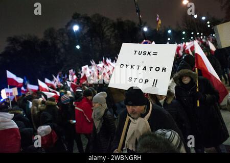 I manifestanti tengono un cartello anti-Tusk e sventolano bandiere polacche durante la manifestazione. L'opposizione di destra della Polonia, frustrata per la sua recente perdita di potere, ha esortato i suoi sostenitori a protestare contro le iniziative del nuovo governo filo-europeo di prendere il controllo delle emittenti statali e dell'agenzia di stampa statale. Il partito legge e giustizia (PiS), che governò per otto anni prima di perdere le elezioni parlamentari di ottobre, chiese una protesta sotto lo slogan "protesta dei polacchi liberi" (protesta Wolnych Polakow) fuori dal parlamento. Ha descritto la protesta come una difesa della democrazia e dei mezzi di comunicazione liberi, in modo invisibile Foto Stock