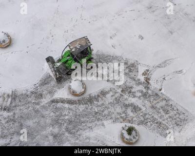 La piccola spazzaneve pulisce e rimuove la neve da un cortile e dal parcheggio Foto Stock