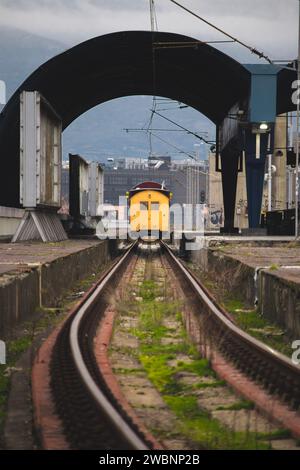 Stazione ferroviaria abbandonata con un vecchio vagone giallo/vagone ferroviario e un treno su un treno arrugginito Foto Stock